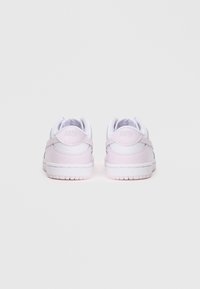 Nike sportcipő világos rózsaszín és fehér színben, sima bőr felsőrésszel, párnázott gallérral és texturált gumitalppal. Minimális márkázási részlet.