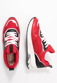 Baskets rouges avec des accents noir et blanc, en matériaux mesh et cuir, semelle épaisse, détail argenté au talon et lacets blancs.