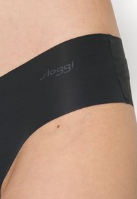 Zwarte naadloze hipster slip van Sloggi, met een gladde elastische stof en een lage taille. Subtiele logo op de tailleband.