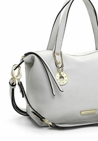 Sac à main en cuir blanc avec doubles poignées, chaîne dorée et breloque ronde, bandoulière amovible et plaque de marque dorée à l’avant.