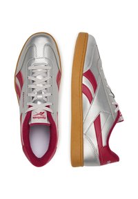 Srebrne trampki z czerwonymi akcentami, o skórzanym wyglądzie, z gumową podeszwą i okrągłym noskiem. Zawierają sznurowadła oraz markowy język.