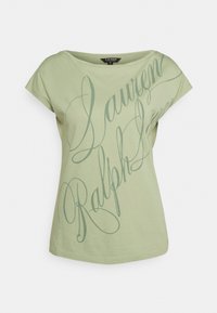 T-shirt en coton vert clair à coupe décontractée, avec un texte graphique en cursive vert foncé, col rond et manches courtes.