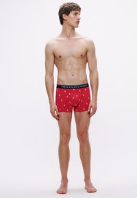 Chiloți boxer roșii cu o talie închisă la culoare, având logo-ul "POLO RALPH LAUREN". Țesătura are o textură fină cu mici logo-uri de cal dispuse într-un model repetitiv.