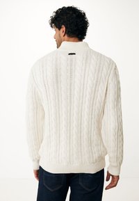 Pull en tricot blanc avec un col montant, un motif texturé et des bords côtelés, présenté sous un angle arrière.