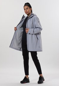 Lichtgrijze waterdichte jas met een capuchon, voorzien van een voorrits, ruime zakken en een gladde, textuurachtige binnenvoering.