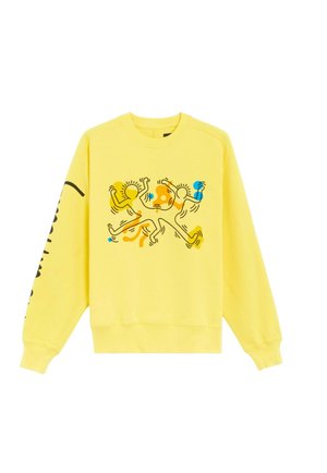 Sudadera amarilla con mangas largas y puños de canalé. El diseño presenta figuras abstractas en naranja, azul y negro en la parte frontal.