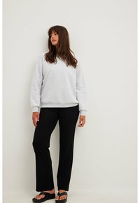 Gaiši pelēks sudrabs ar ribotām piedurknēm un apakšmalu, apvienots ar melnām platiem biksēm un melniem slaidiem sandales. Ikdienišķs un ērts apģērbs.