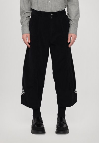 Pantaloni largi din corduroy negri, cu talie înaltă, având o închidere cu nasture frontal și broderie albă în dungi la tiv.