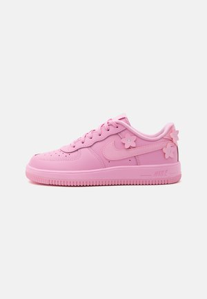 Ružová nízka teniska so šnúrkami, logom Nike swoosh a ozdobnými ružovými kvetinovými aplikáciami na boku a päte.
