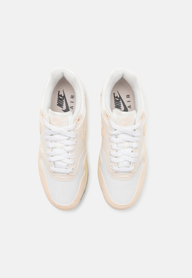 Baskets Nike Air en blanc et pêche doux. Comprennent une tige en mesh et synthétique, des lacets ronds, un col rembourré et une semelle amortie.