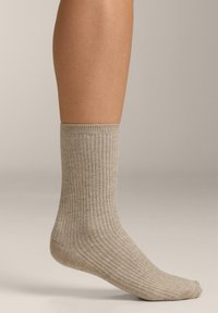 Beige színű, bordázott szövetű zokni, puha anyagból készült, texturált felülettel és megerősített orral és sarokrésszel a tartósság érdekében.