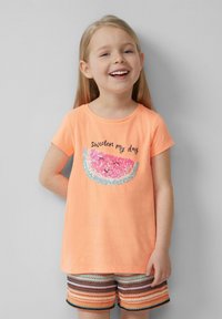 Korte mouwen, koraalkleurig T-shirt met een paillettenwatermeloenontwerp. Tekst: "maak mijn dag zoeter." Combinatie met multicolore gestreepte shorts.