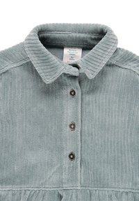 Vestito in corda leggermente azzurro con collo a camicia, chiusura a bottoni frontale e orlo arricciato. Presenta righe verticali testurizzate.