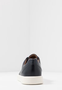 Baskets en cuir bleu marine au design profilé, semelle en caoutchouc blanche, col rembourré et accents intérieurs marron. Couture détaillée au talon.