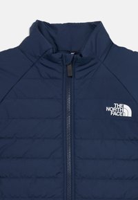 Marineblaue isolierte Jacke mit hohem Kragen, horizontalen Nähten, Reißverschluss und weißem Logo auf der linken Brust. Glatte Textur.