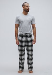 Grå V-hals T-skjorte med en liten logo sammen med svart-hvite rutete flanellbukser, med justerbar snor i midjen.