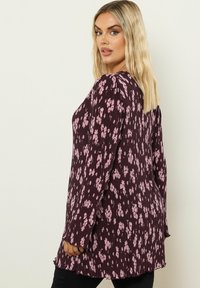 Blusa de manga larga en burdeos profundo con un patrón floral en rosa claro, con un cuello redondo y un diseño fluido.