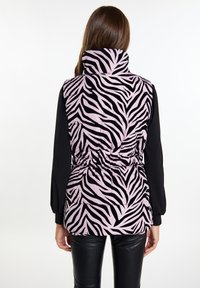 Lilla og sort zebra-mønstret puffervest med høj krave, samlet talje og sorte lange ærmer, båret over mørke leggings.