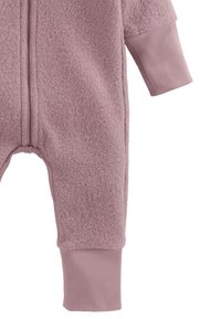 Zacht roze fleece baby jumpsuit met ribgebreide boorden en een rits aan de voorkant, vanaf het midden van de romp tot de benen weergegeven tegen een witte achtergrond.