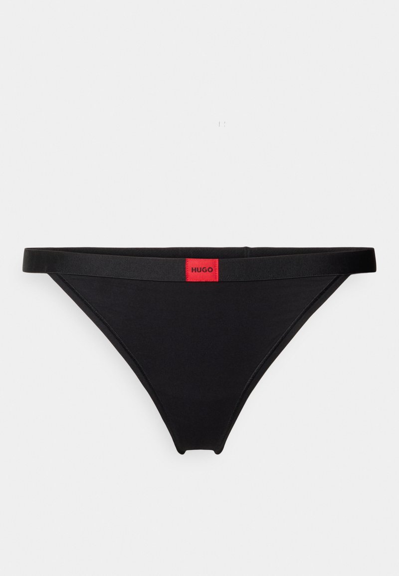 Tanga preta com cintura elástica brilhante, logótipo vermelho proeminente "HUGO", textura suave e design minimalista.
