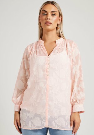 Lyserød gennemsigtig bluse med blomsterbroderi, knaplukning, volang-udskæring og lange puffede ærmer. Tekstureret stof med en blød, glat overflade.
