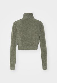 Przycięty zielony sweter z wysokim kołnierzem, ściągaczami na mankietach i teksturowaną dzianiną. Widok z tyłu ukazuje dopasowany krój.