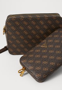 Braun gemusterte Taschen aus strukturiertem Material; die größere Tasche hat goldene Beschläge und einen Reißverschluss, die kleinere Geldbörse weist das Logo und ein passendes Design auf.