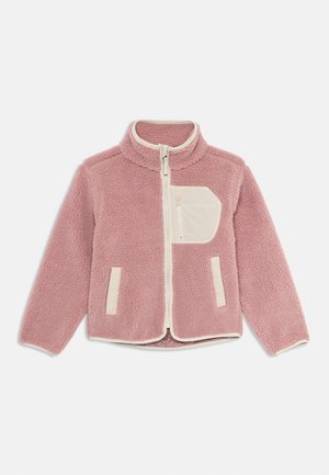 Veste en polaire rose avec des finitions beiges, fermeture éclair sur toute la longueur à l'avant, deux poches avant, et une poche zippée beige sur la poitrine, sur fond blanc.