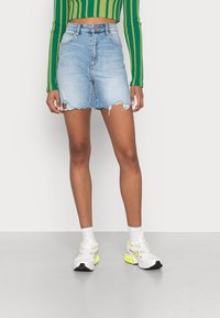 Vaaleansininen farkku minihame, jossa on repsottava helma; yhdistetty vihreään ja siniseen raidalliseen pitkähihaiseen paitaan sekä valkoisiin lenkkareihin, joissa on keltaisia yksityiskohtia.