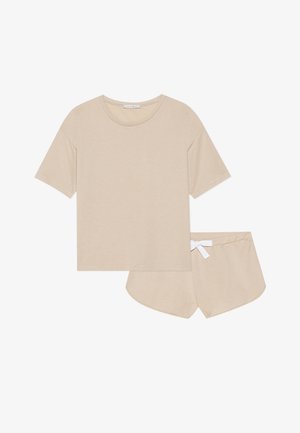 Bežinis medvilninis laisvalaikio drabužių komplektas, kuriame yra trumpomis rankovėmis marškinėliai su apvalia iškirpte ir atitinkamos šortai su balta raištelių juosta.