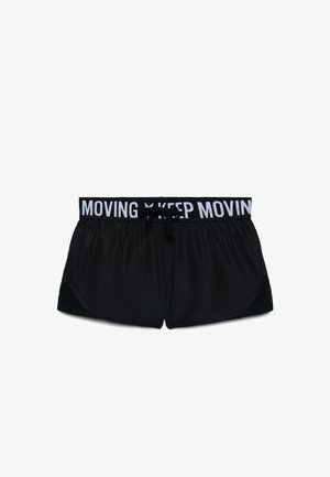 Czarne sportowe spodenki z białym elastycznym pasem z napisem "KEEP MOVING" oraz czarnym sznurkiem do wiązania na środku.