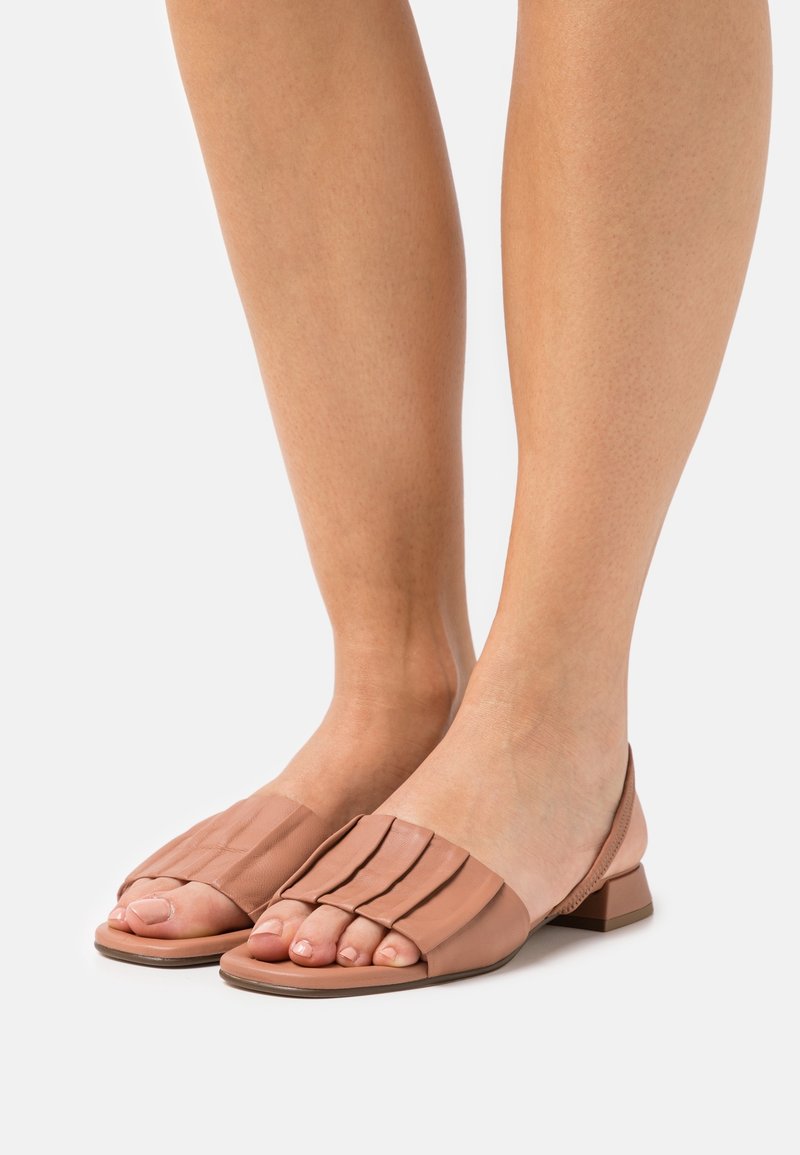 Tan slip-on sandaalit, joissa on pleatattu nahkainen päällinen, avopohjallinen muotoilu ja matala tukikorko vakauden takaamiseksi. Sujuva pinta ja minimalistinen tyyli.
