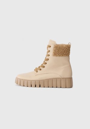 Beige high-top sneaker with a textured tan fleece collar, sturdy rubber sole, and rounded toe. Features round laces and reinforced stitching.