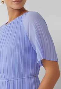 Helllila gefälteter Kleid mit kurzen Ärmeln und einem runden Halsausschnitt. Glatte Textur mit einem taillierten Detail.