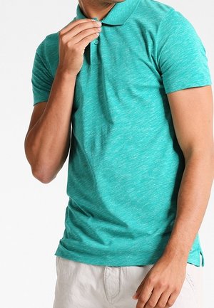 Camiseta tipo polo de manga corta en turquesa con un patrón jaspeado y texturizado. Cuenta con cuello y tapeta de tres botones, usada de manera casual.