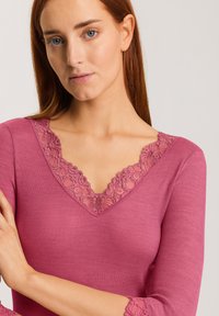 Maglia a maniche lunghe in tessuto a coste rosa con scollatura a V in pizzo a motivo ondulato e bordi in pizzo ai polsini delle maniche. Tessuto morbido con un design aderente.
