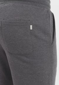 Pantalones de chándal grises hechos de una tela suave, con un bolsillo trasero con un acabado cosido y una pequeña etiqueta "BLEND" en el costado.