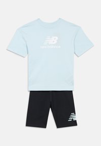 Lyseblå New Balance t-shirt med korte ærmer og logo på brystet, parret med sorte shorts med et matchende logo på venstre ben.
