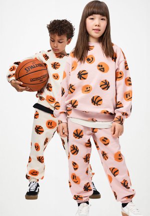Sweatshirts and sweatpants in pastel pink and cream featuring black and orange basketball and smiley face prints. Soft cotton material, relaxed fit.