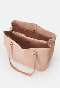 Rosa texturerad läderhandväska med guldhardware, dubbla handtag och flera fack, inklusive ett blixtlåsfack inuti.