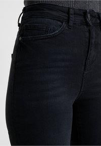 Černé džíny z denimu s úzkým střihem, designem se pěti kapsami a jemnými švy. Vyrobeny z odolného, strukturovaného materiálu.