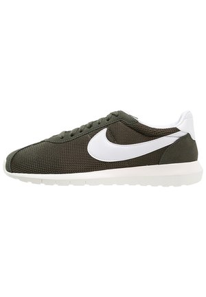 Baskets en tricot vert olive à profil bas avec logo Nike swoosh blanc, languette de talon blanche et semelle blanche.