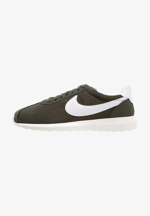 Niski profil zielono-oliwkowy dziany sneaker z białym logo Nike swoosh, białą pętelką na pięcie i białą podeszwą.