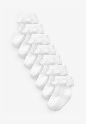 Witte enkelkousen met een kanten ruffle aan de boord, een gestructureerd lichaam en een gladde teenpartij. Acht paar netjes op een rij geordend.
