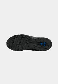 Semelle de chaussure de sport noire en caoutchouc texturé pour une meilleure adhérence, avec des accents bleus et un motif de semelle multidirectionnel.