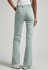 Light green flared jeans made of cotton blend. Features decorative stitching on back pockets and a classic waistband.