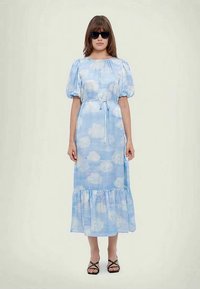 Svetlo modra obleka z vzorcem oblakov, naborki na rokavih, pasni trak in naguban rob. Nosite s črnimi sončnimi očali in črnimi sandalami na vezalke.