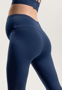 Námornícke modré legíny s vysokým pásom vyrobené z hladkého, elastického materiálu, s kontúrovaným strihom a minimálnym brandingom na pásku.