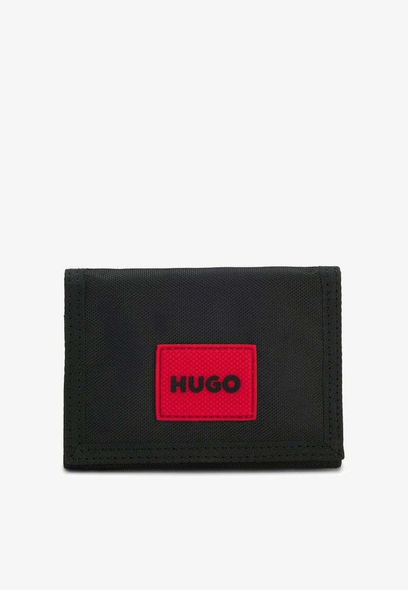 Portefeuille en tissu noir à surface texturée, avec un patch rectangulaire rouge portant l'inscription "HUGO" en relief. Design compact et rectangulaire.
