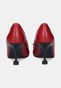 Zapatos de tacón alto de cuero rojo con punta afilada y tacón de aguja negro brillante. Textura suave y diseño minimalista.